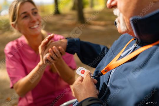 grandfather holding an SOS emergency button while a caregiver smiles at him in an outdoor setting  : Stock Photo or Stock Video Download rcfotostock photos, images and assets rcfotostock | RC Photo Stock.: