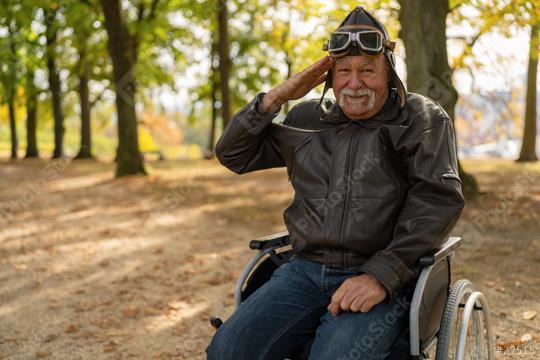 grandfather in a wheelchair, dressed in aviator gear, saluting playfully in a park with autumn trees in the background. Dementia retirement home concept image  : Stock Photo or Stock Video Download rcfotostock photos, images and assets rcfotostock | RC Photo Stock.: