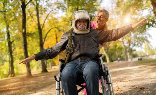 grandfather in an astronaut helmet and leather jacket extends his arms as if flying, with a nurse laughing beside him. Dementia retirement home concept image  : Stock Photo or Stock Video Download rcfotostock photos, images and assets rcfotostock | RC Photo Stock.: