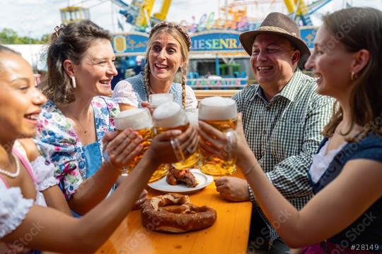 Group of Friends cheerfully toasting with beer mugs at oktoberfest festival on a beer tent table, amusement rides in the background  : Stock Photo or Stock Video Download rcfotostock photos, images and assets rcfotostock | RC Photo Stock.: