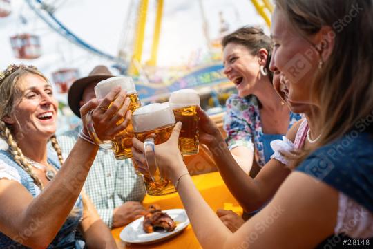 Group of friends laughing and toasting with beer mugs at a oktoberfest festival in munich, amusement park rides in the background  : Stock Photo or Stock Video Download rcfotostock photos, images and assets rcfotostock | RC Photo Stock.: