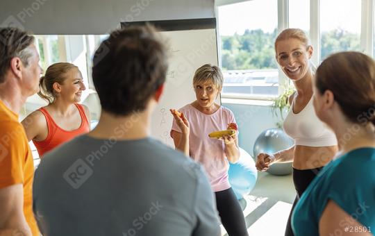 Group of people discussing with a female trainer about nutritional advice holding a banana in a gym setting  : Stock Photo or Stock Video Download rcfotostock photos, images and assets rcfotostock | RC Photo Stock.: