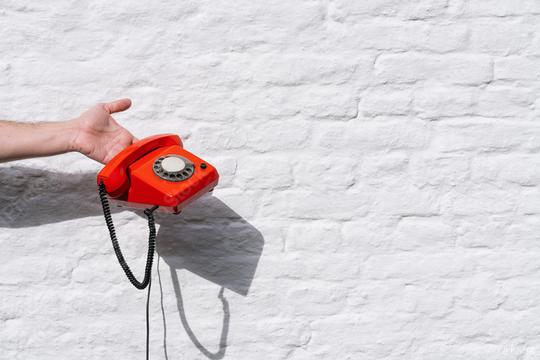 hand holding a Red telephone against a white brick wall  : Stock Photo or Stock Video Download rcfotostock photos, images and assets rcfotostock | RC Photo Stock.: