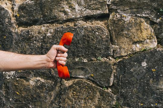 hand holding a red telephone receiver against a stone wall  : Stock Photo or Stock Video Download rcfotostock photos, images and assets rcfotostock | RC Photo Stock.: