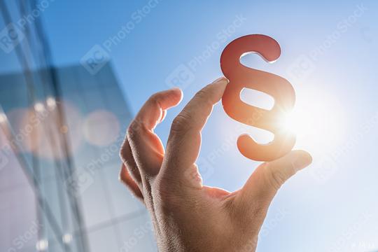 Hand holds paragraph symbol in the sun in to the sky with office building  : Stock Photo or Stock Video Download rcfotostock photos, images and assets rcfotostock | RC Photo Stock.:
