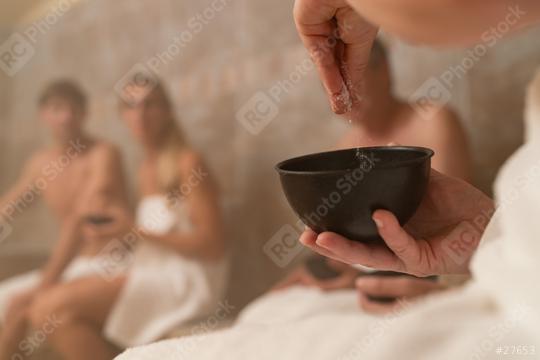 Hand sprinkling salt from a bowl with blurry people in the background in a steam room. Spa Wellness hotel concept image  : Stock Photo or Stock Video Download rcfotostock photos, images and assets rcfotostock | RC Photo Stock.: