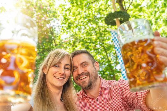 Happy Couple looking and smiling at camera toast beer mugs in a Bavarian beer garden at summer  : Stock Photo or Stock Video Download rcfotostock photos, images and assets rcfotostock | RC Photo Stock.: