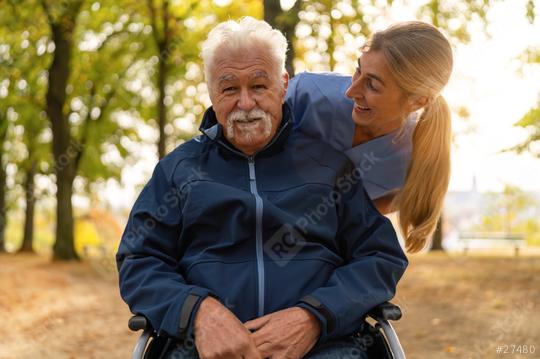 Happy elderly man in a wheelchair with a nurse leaning over him, both smiling in a park with autumn leaves  : Stock Photo or Stock Video Download rcfotostock photos, images and assets rcfotostock | RC Photo Stock.: