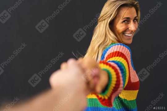 Happy excited woman pulling hand wearing colorful rainbow sweater standing over black background, lgbt celebrating concept image  : Stock Photo or Stock Video Download rcfotostock photos, images and assets rcfotostock | RC Photo Stock.: