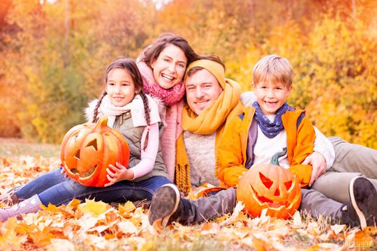 Happy family of four sitting in a park surrounded by autumn leaves, holding carved pumpkins, enjoying a festive fall day with warm scarves and jackets, and vibrant fall foliage in the background  : Stock Photo or Stock Video Download rcfotostock photos, images and assets rcfotostock | RC Photo Stock.: