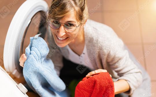 Happy Housewife Loads red and blue hand towel in to the washing machine or dryer. Housekeeping and household concept image  : Stock Photo or Stock Video Download rcfotostock photos, images and assets rcfotostock | RC Photo Stock.: