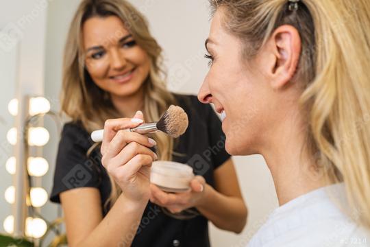 Happy makeup artist applying makeup with powder brusht to customer in beauty salon  : Stock Photo or Stock Video Download rcfotostock photos, images and assets rcfotostock | RC Photo Stock.: