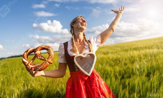 Happy party woman in Bavarian dirndl with a gingerbread heart, holding a pretzel in a wheat field celebrating Oktoberfest or dult festival in munich, with copyspace for your individual text.  : Stock Photo or Stock Video Download rcfotostock photos, images and assets rcfotostock | RC Photo Stock.: