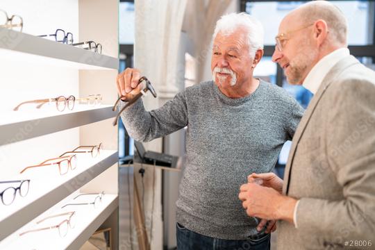 Happy senior man holding new glasses with optician beside him. both looking at eyewear display in an optical shop.  : Stock Photo or Stock Video Download rcfotostock photos, images and assets rcfotostock | RC Photo Stock.: