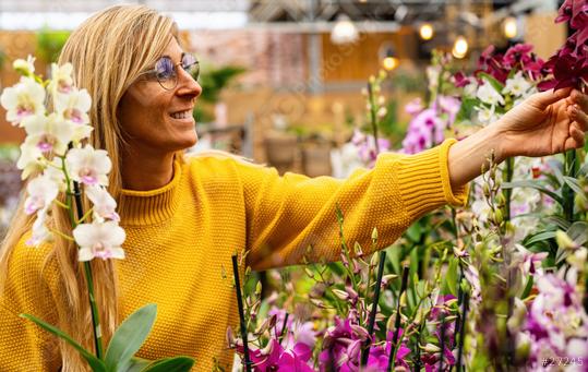 Happy woman admiring orchid flowers in a Garden Center to buy it for their apartment. Shopping in a greenhouse concept image  : Stock Photo or Stock Video Download rcfotostock photos, images and assets rcfotostock | RC Photo Stock.: