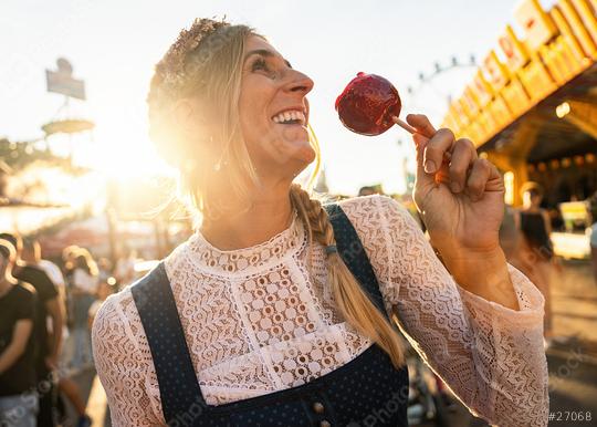 Happy woman eating candy apple on a Bavarian fair or oktoberfest or duld in Dirndl at germany   : Stock Photo or Stock Video Download rcfotostock photos, images and assets rcfotostock | RC Photo Stock.: