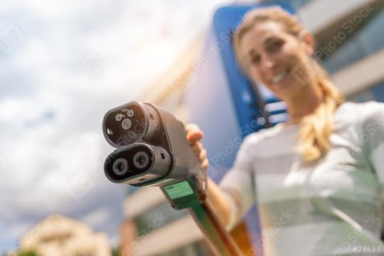 Happy woman holding a DC CCS2 EV charging connector on Hyperchar  : Stock Photo or Stock Video Download rcfotostock photos, images and assets rcfotostock | RC Photo Stock.: