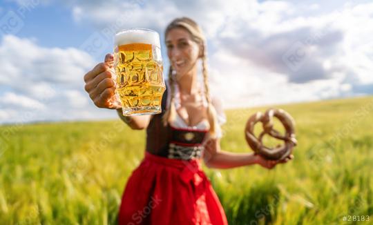 Happy woman in traditional Bavarian tracht showing a beer mug and pretzel in a wheat field celebrating Oktoberfest festival in munich.  : Stock Photo or Stock Video Download rcfotostock photos, images and assets rcfotostock | RC Photo Stock.: