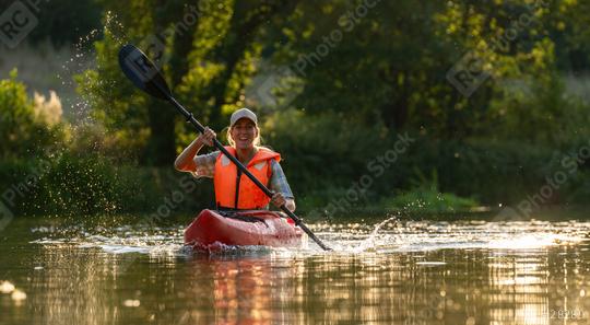 Happy woman kayaking on a sunny day, splashing water with her paddle, wearing an orange life jacket at summer.Kayak Water Sports concept image  : Stock Photo or Stock Video Download rcfotostock photos, images and assets rcfotostock | RC Photo Stock.: