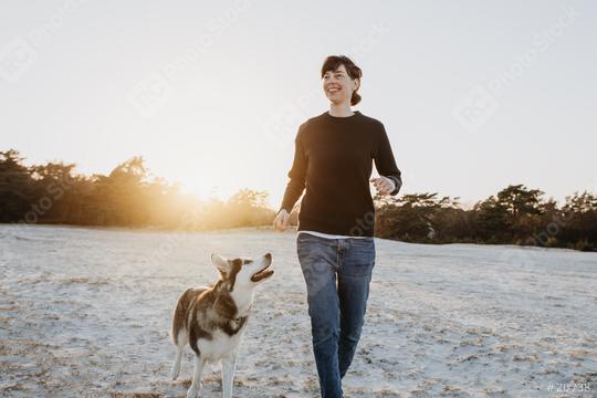 Happy woman running across the sand on the beach with cheerful dog at sunset.They have fun together, are good friends, and enjoy their vacation and life.  : Stock Photo or Stock Video Download rcfotostock photos, images and assets rcfotostock | RC Photo Stock.: