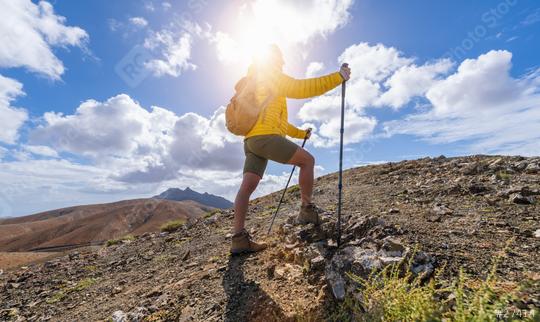 Hiker in yellow jacket climbing a mountain path against a sunny, cloud-filled sky  : Stock Photo or Stock Video Download rcfotostock photos, images and assets rcfotostock | RC Photo Stock.: