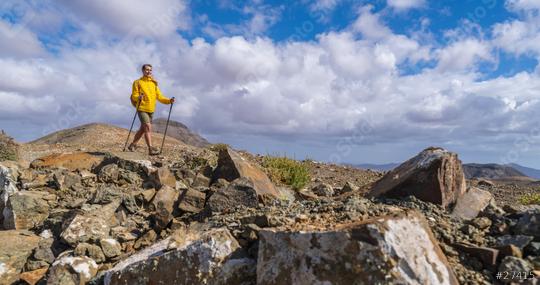 Hiker in yellow on rocky mountain terrain with cloudy blue sky in the background  : Stock Photo or Stock Video Download rcfotostock photos, images and assets rcfotostock | RC Photo Stock.: