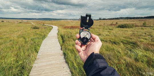 Hiker man searching direction with a compass in a bog landscape with wooden trail. View of hands. Point of view shot.  : Stock Photo or Stock Video Download rcfotostock photos, images and assets rcfotostock | RC Photo Stock.: