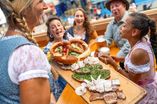 Joyful waitress serving traditional German food on a wooden platter to a group of friends at oktoberfest festival or dult in germany  : Stock Photo or Stock Video Download rcfotostock photos, images and assets rcfotostock | RC Photo Stock.: