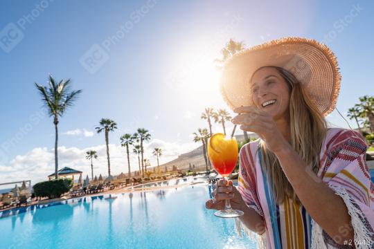 Joyful woman in a straw hat enjoying a colorful cocktail by a sunny poolside with palm trees in the background at a spanish hotel  : Stock Photo or Stock Video Download rcfotostock photos, images and assets rcfotostock | RC Photo Stock.: