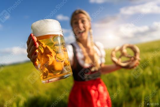 Joyful woman in Bavarian dress presenting a beer and pretzel outdoors in a field´ready for Oktoberfest festival in munich, germany  : Stock Photo or Stock Video Download rcfotostock photos, images and assets rcfotostock | RC Photo Stock.: