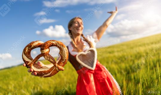 Joyful woman in Bavarian tracht with a gingerbread heart, holding a pretzel in a wheat field celebrating Oktoberfest or dult festival in munich.  : Stock Photo or Stock Video Download rcfotostock photos, images and assets rcfotostock | RC Photo Stock.: