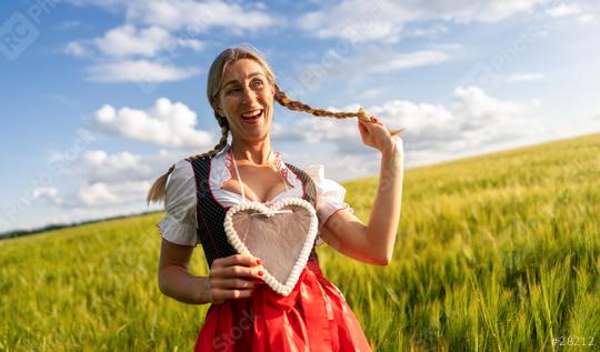 Laughing woman in Bavarian costume playing with her braid and holding a gingerbread heart in a wheat field celebrating Oktoberfest in munich, with copyspace for your individual text.  : Stock Photo or Stock Video Download rcfotostock photos, images and assets rcfotostock | RC Photo Stock.: