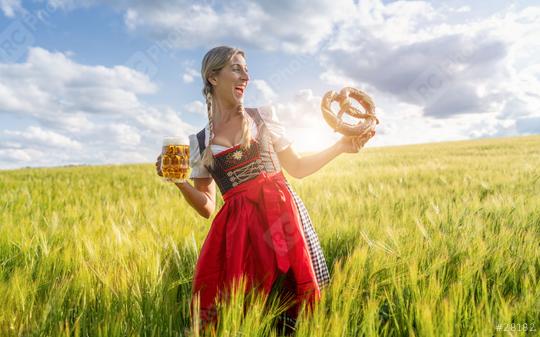 Laughing woman in traditional German tracht with beer and pretzel in a wheat field ready for Oktoberfest in munich.  : Stock Photo or Stock Video Download rcfotostock photos, images and assets rcfotostock | RC Photo Stock.: