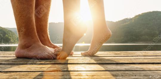 Legs on jetty. A young loving couple hugging and kissing on the pier on a lake at sunset. Two lovers, man and woman barefoot near the water on a jetty. Happy love moments together.  : Stock Photo or Stock Video Download rcfotostock photos, images and assets rcfotostock | RC Photo Stock.: