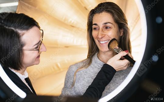 makeup assistant powders a models face posing at camera through ring light lamp. Photo shooting with ring light or movie set location  : Stock Photo or Stock Video Download rcfotostock photos, images and assets rcfotostock | RC Photo Stock.: