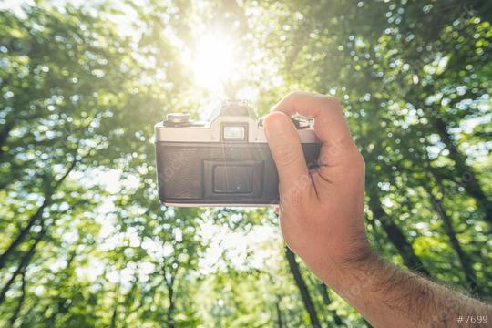 male hand holding a vintage camera against the forest with explosive sun to take a picture, point of view perspective.  : Stock Photo or Stock Video Download rcfotostock photos, images and assets rcfotostock | RC Photo Stock.: