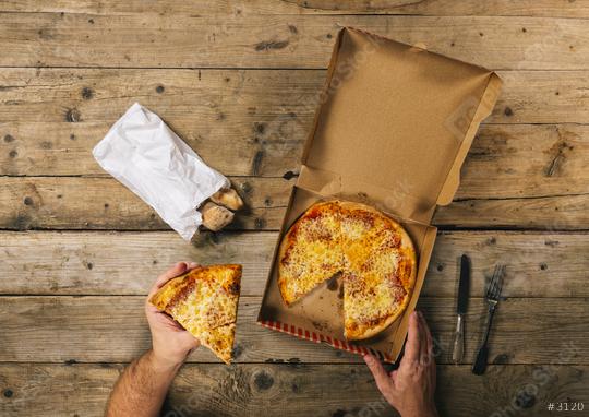 male hands holding pizza piece with delivery box ready to eat over a wooden table. Top view  : Stock Photo or Stock Video Download rcfotostock photos, images and assets rcfotostock | RC Photo Stock.:
