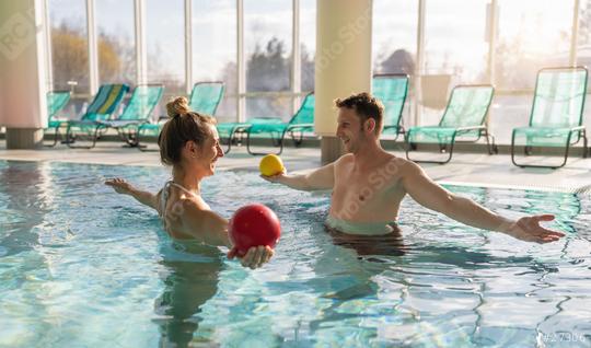 Male trainer conducting aquatic therapy with a female client using exercise balls in a sunny pool  : Stock Photo or Stock Video Download rcfotostock photos, images and assets rcfotostock | RC Photo Stock.: