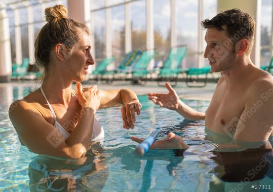 Male trainer explaining exercise to female client in pool, both holding resistance bars, with sunlight  : Stock Photo or Stock Video Download rcfotostock photos, images and assets rcfotostock | RC Photo Stock.: