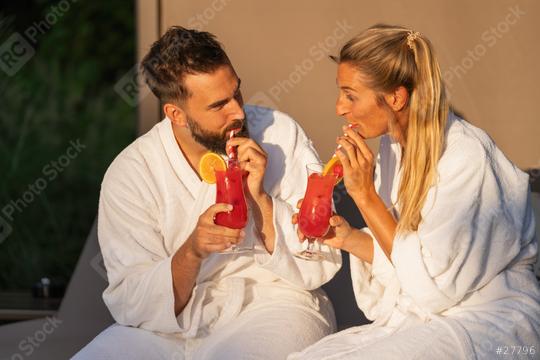 Man and woman in white robes sipping cocktails in golden hour light at spa hotel resort  : Stock Photo or Stock Video Download rcfotostock photos, images and assets rcfotostock | RC Photo Stock.: