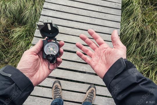 Man hold a compass and searching direction the direction on a wooden boardwalk, point of view.  : Stock Photo or Stock Video Download rcfotostock photos, images and assets rcfotostock | RC Photo Stock.: