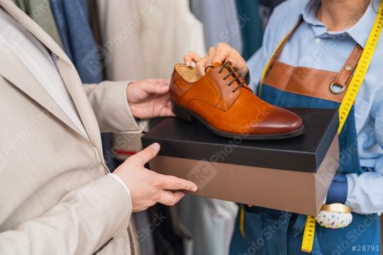 man holding a tan dress shoe above a shoe box with a tailor holding a tape measure  : Stock Photo or Stock Video Download rcfotostock photos, images and assets rcfotostock | RC Photo Stock.: