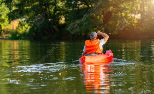 Man in an orange life jacket paddling a red kayak on a calm river, surrounded by lush greenery in sunlight. Kayak Water Sports concept image  : Stock Photo or Stock Video Download rcfotostock photos, images and assets rcfotostock | RC Photo Stock.: