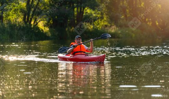 Man in orange life jacket kayaking in red kayak on a river, golden sunlight reflecting on water. Kayak Water Sports concept image  : Stock Photo or Stock Video Download rcfotostock photos, images and assets rcfotostock | RC Photo Stock.: