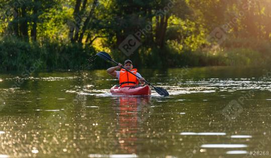 Man in orange life jacket paddles a red kayak through calm river waters, dappled with sunlight and surrounded by lush foliage in bavaria germany. Kayak Water Sports concept image  : Stock Photo or Stock Video Download rcfotostock photos, images and assets rcfotostock | RC Photo Stock.: