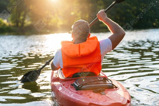 Man in orange life jacket paddling a red kayak on a shimmering river during sunset at summer in germany. Kayak Water Sports concept image  : Stock Photo or Stock Video Download rcfotostock photos, images and assets rcfotostock | RC Photo Stock.: