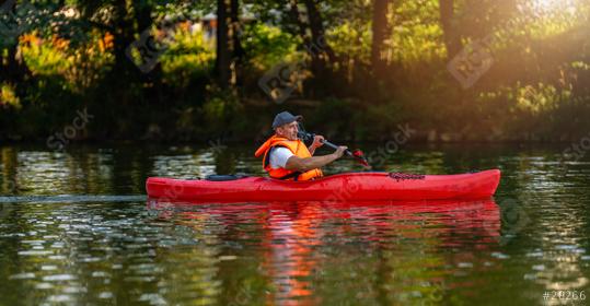 Man kayaking alone in a red kayak on a serene river, surrounded by lush greenery in glowing evening light. Kayak Water Sports concept image  : Stock Photo or Stock Video Download rcfotostock photos, images and assets rcfotostock | RC Photo Stock.: