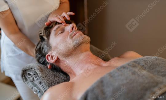Man relaxing during a head massage in a spa with therapist