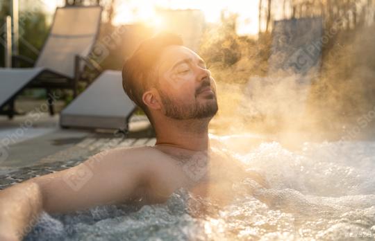 Man relaxing in a hot tub with steam rising around him at sunset at spa resort hotel  : Stock Photo or Stock Video Download rcfotostock photos, images and assets rcfotostock | RC Photo Stock.: