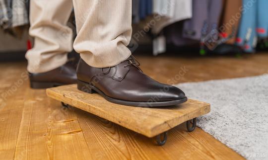 Man trying on brown leather shoes, standing on one foot on a wooden board  : Stock Photo or Stock Video Download rcfotostock photos, images and assets rcfotostock | RC Photo Stock.: